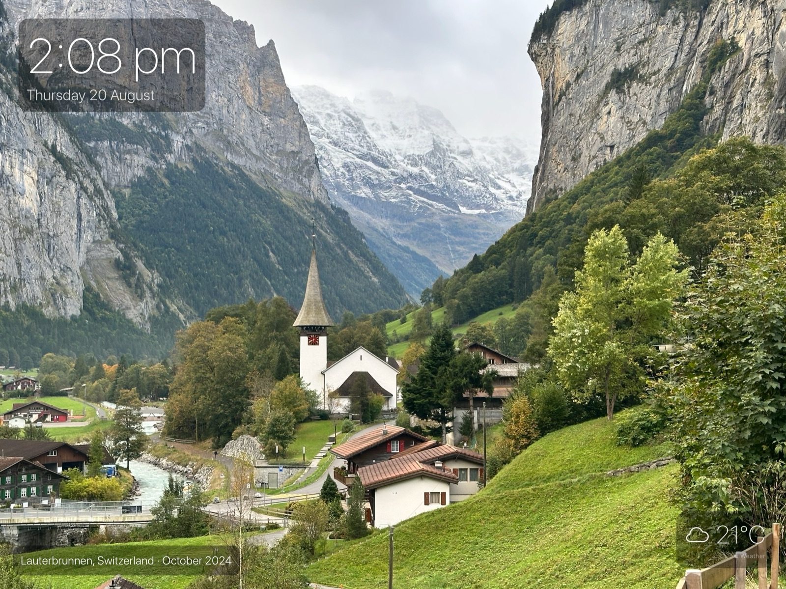 A daylight photograph of the Lauterbrunnen valley in Switzerland filling the iPad screen, with the time and date in the top corner.